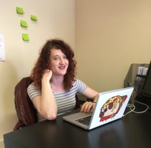 Jessica Perren sat at desk with laptop.