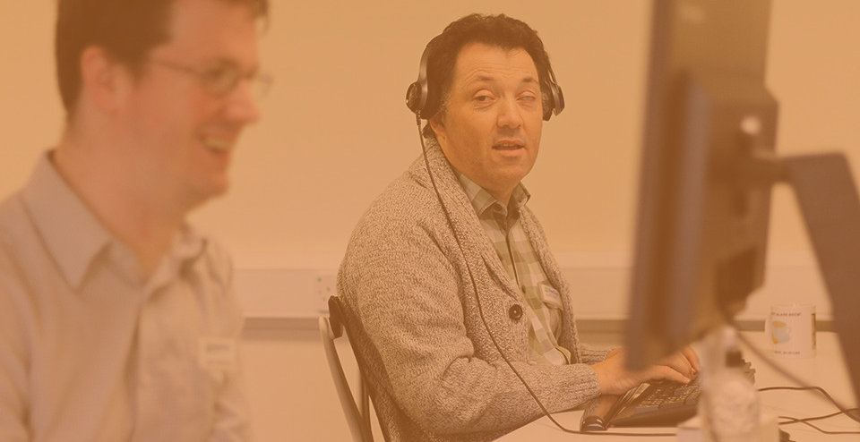 Alan Sleat, from the SYAS team, sat in front on a computer and wearing a headset - testing websites.