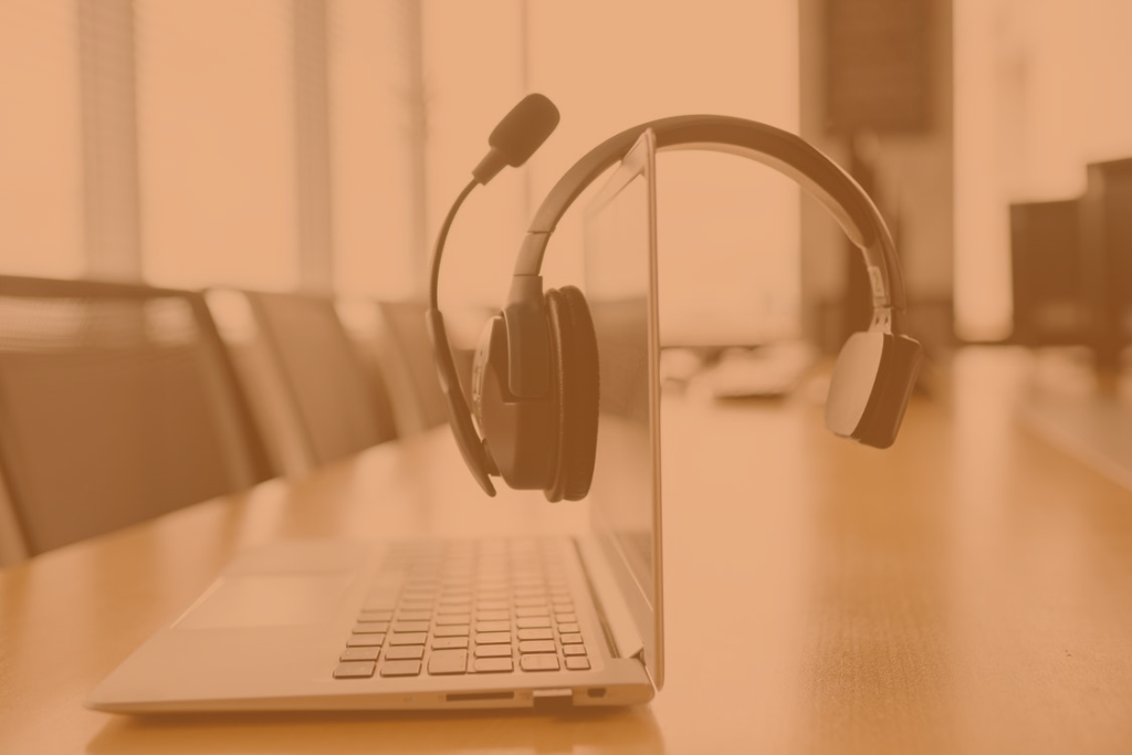 a headset laying on top of a laptop, within an office setting