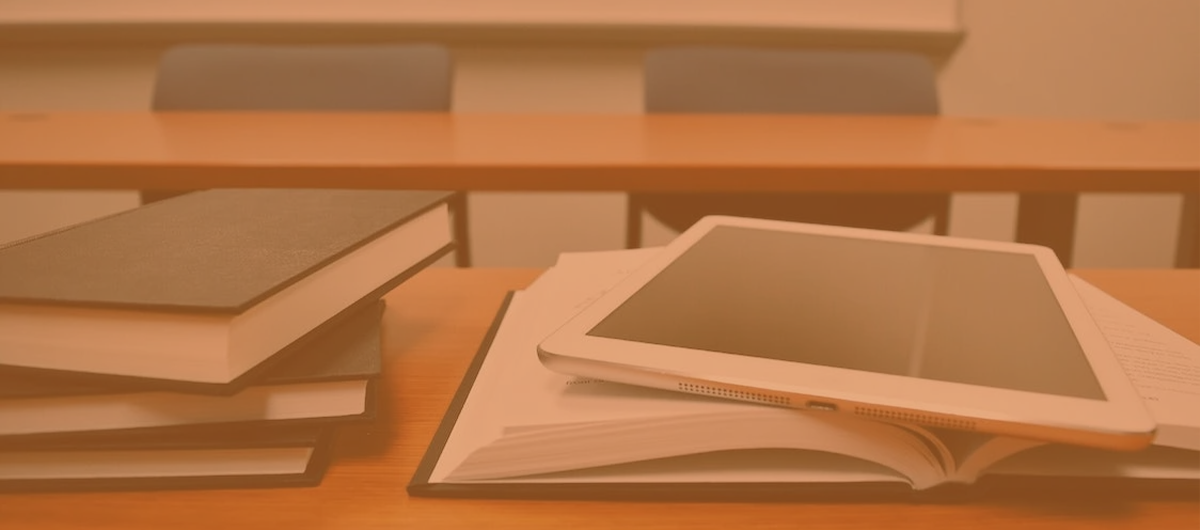 a tablet sat on top of a book, on a desk in a university setting