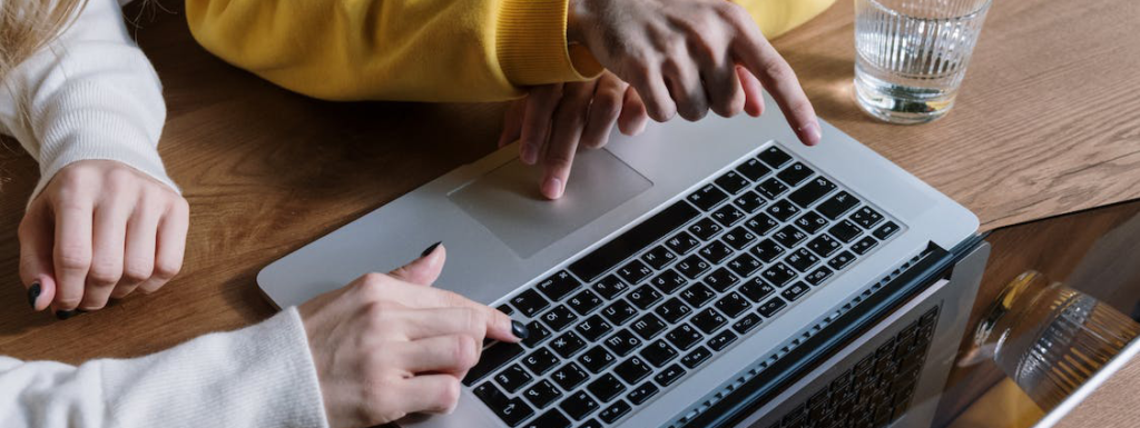 two people sat around a laptop pointing at the screen