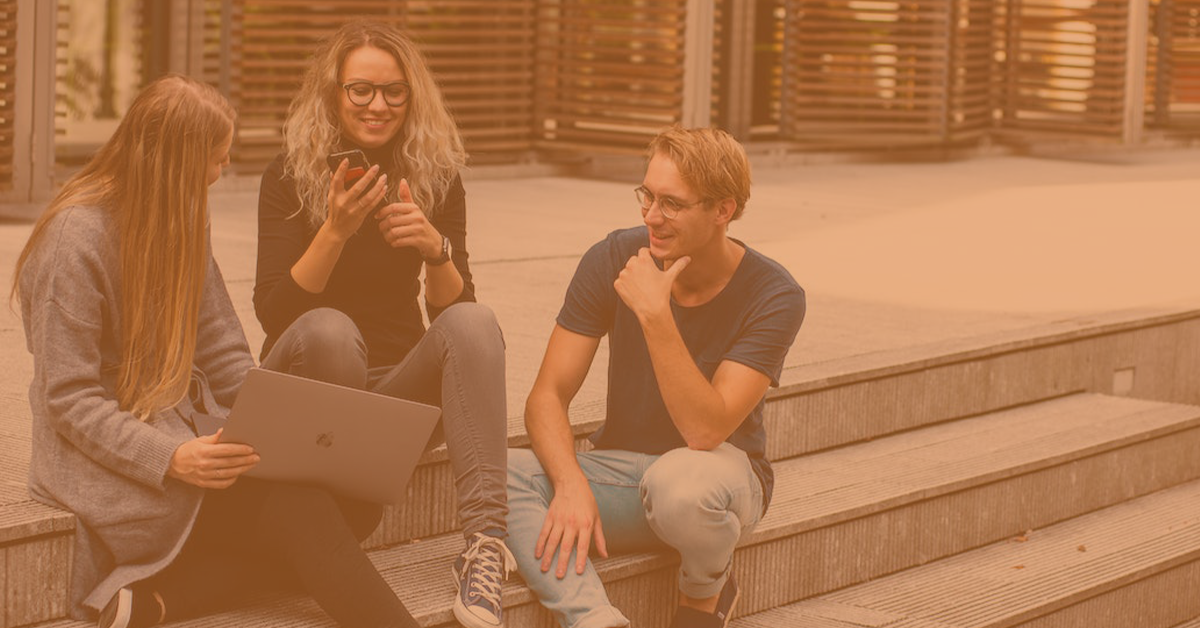 students sat on steps with a laptop smiling