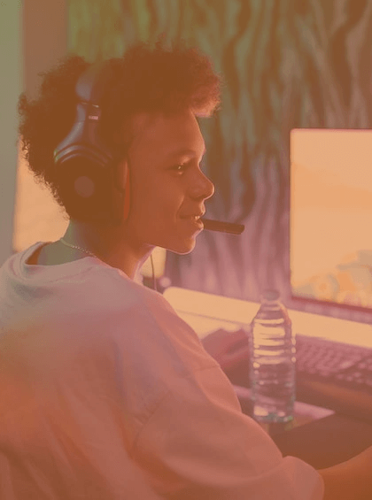 a young boy sat with a headset on, in front of his gaming PC