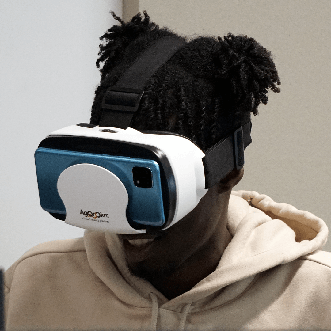 A student sat smiling whilst wearing a VR headset 