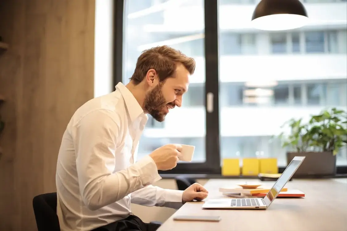 a man on a laptop in an office smiling