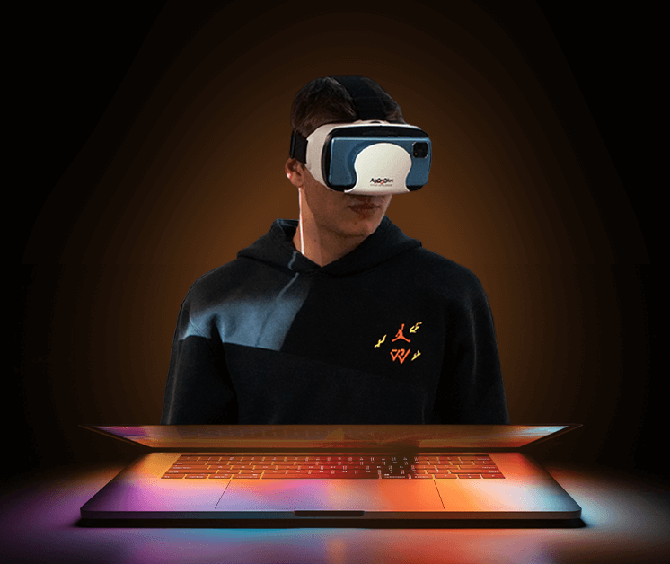 a student wearing a VR headset, whilst stood in front of a glowing laptop