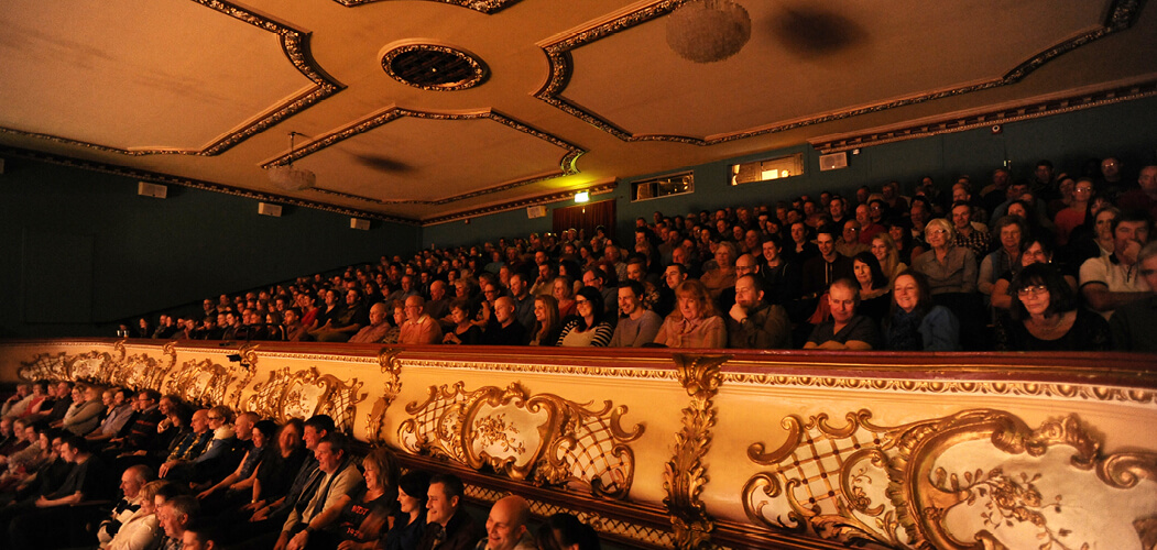 an audience watching a theatre show on the top tier