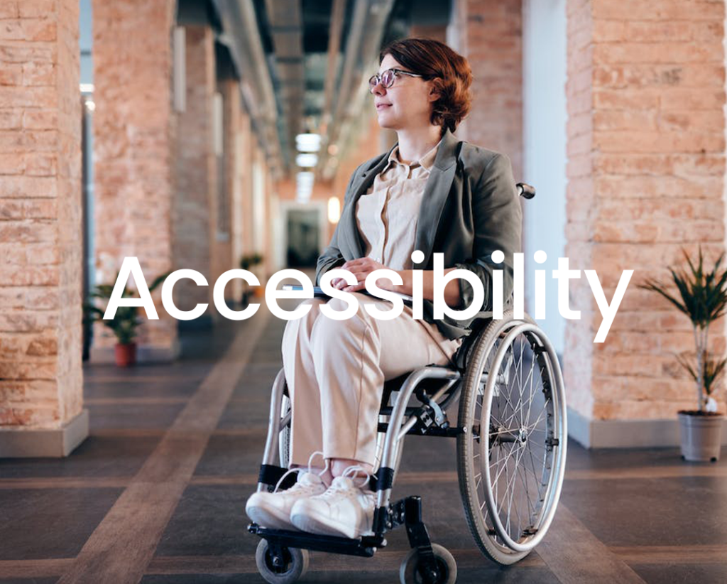 a wheelchair user in an office environment, which has the word "accessibility" in white letters that is hard to read against the background