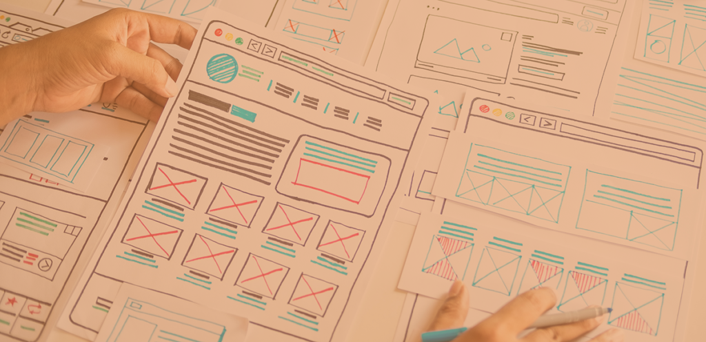 a series of sketched wireframe drawings laid out across a table, planning the structure of web pages.